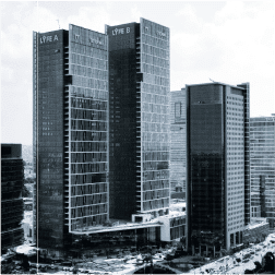 תמונה בשחור-לבן לוכדת נוף עירוני של שלושה רבי קומות מודרניים, כאשר LYFE A ו-LYFE B מעטרות את הגבוהים ביותר. המבנים שמסביב משתנים בגובה ובעיצוב, על רקע שמיים בהירים - סצנה בולטת המזכירה חבר תרגומים אדריכלי.