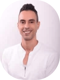 אדם חייכן עם שיער קצר וכהה לובש חולצה לבנה. הם עומדים על רקע בהיר רגיל.