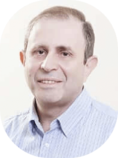 אדם עם שיער קצר לובש חולצת צווארון תכלת, מחייך קלות, ומביט במצלמה. הרקע הוא צבע רגיל ובהיר.