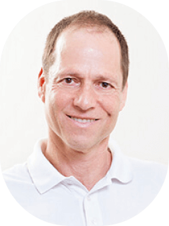 גבר חייכן עם שיער קצר, לבוש בחולצת פולו לבנה, על רקע לבן רגיל.