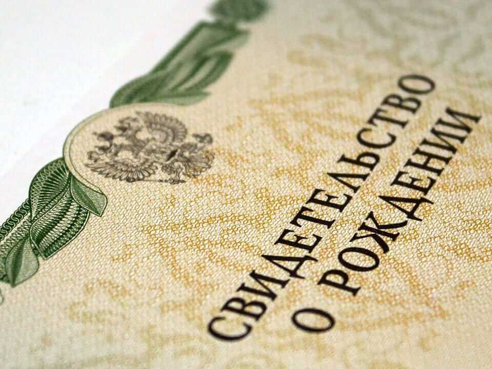 תקריב של תעודת לידה רוסית עם אלמנטים עיצוביים מעוטרים, עם דוגמאות דקורטיביות ירוקות לאורך הקצה ומעיל נשק בחלק העליון. הטקסט ברוסית, מציג בצורה בולטת Свидетельство о рождении, ממתין לתרגום להכרה בינלאומית.