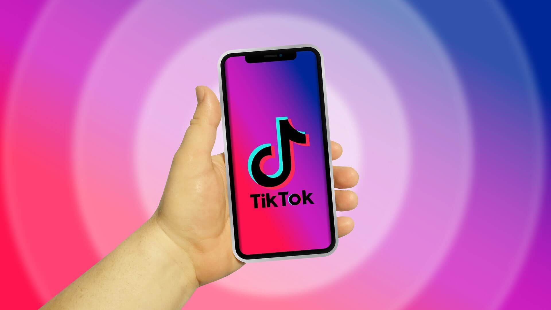 יד מחזיקה סמארטפון עם הלוגו של TikTok בוהק על המסך, על רקע עגול תוסס שטוף גוונים כחולים, ורודים וסגולים.