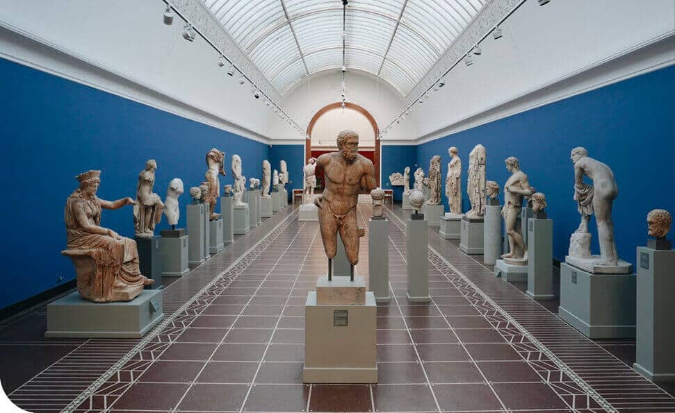 אולם גלריה רחב ידיים עם תקרה מקושתת גבוהה מציג פסלים קלאסיים שונים על כנים. הפסלים כוללים דמויות עומדות ויושבות, מיושרות באופן סימטרי לאורך הקירות הכחולים ומרכז החדר.